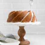 Dairy free lemon pound cake with lemon glaze being drizzled over from a spoon.