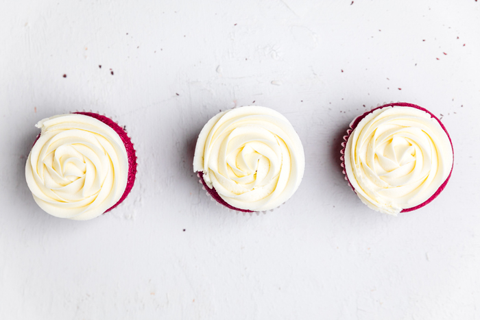 three dairy free red velvet cupcakes with cream cheese frosting.
