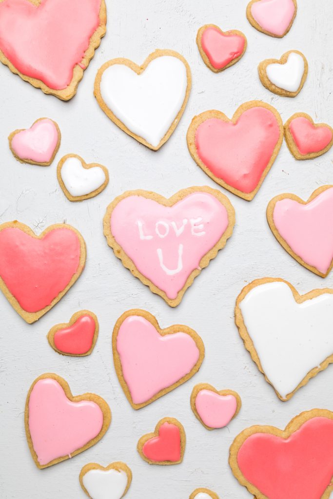 Dairy free heart shaped sugar cookies with pink icing, middle one says love u. 