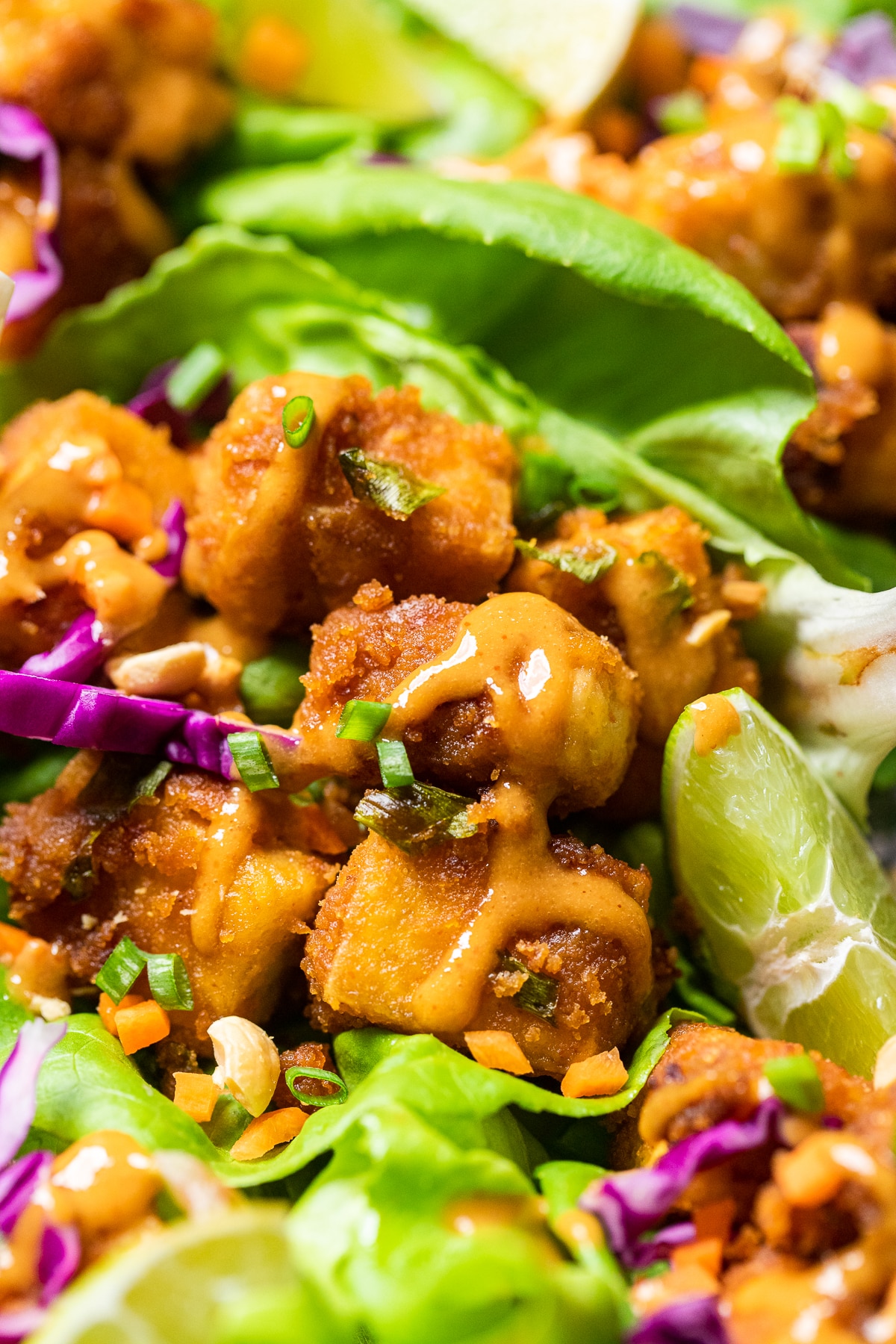 pieces of butter lettuce topped with peanut butter tofu, green onions, red cabbage and extra sauce.