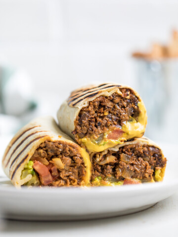 A plate of three vegan cheeseburger wraps halved and on a plate.