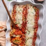 A serving dish of cheesy vegan lasagna roll-ups.