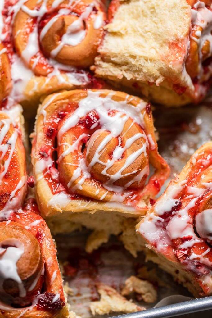 A close of up of one vegan strawberry cinnamon roll with a lemon glaze.