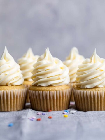 A few vegan vanilla cupcakes with spiraled vegan vanilla frosting on top.